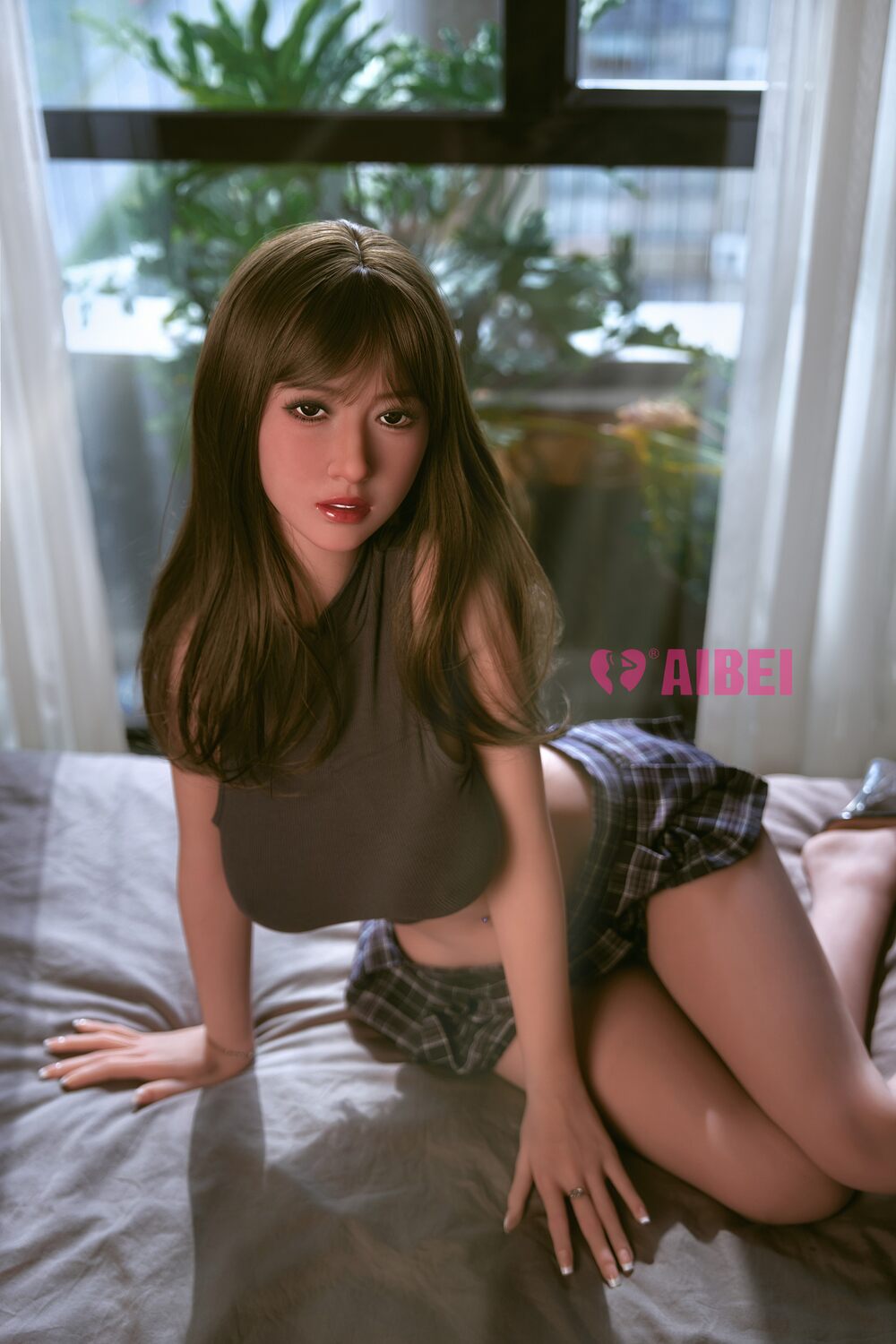 Real doll Freya mit braunem Top und kariertem Minirock in kniender Pose auf dem Bett
