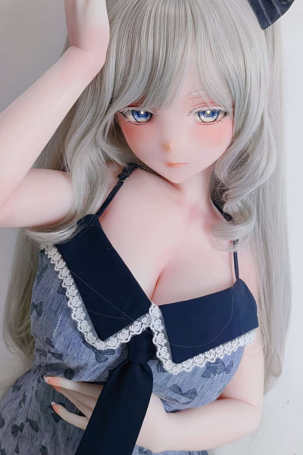 Detailaufnahme der Kaneda Shio Sex Doll mit langen silbernen Haaren und schüchterner Pose im Schlafzimmer