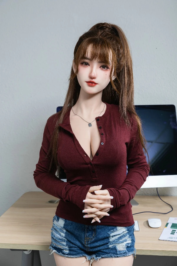 Marlee Sexdoll im dunkelroten Pullover und Jeansshorts am Schreibtisch