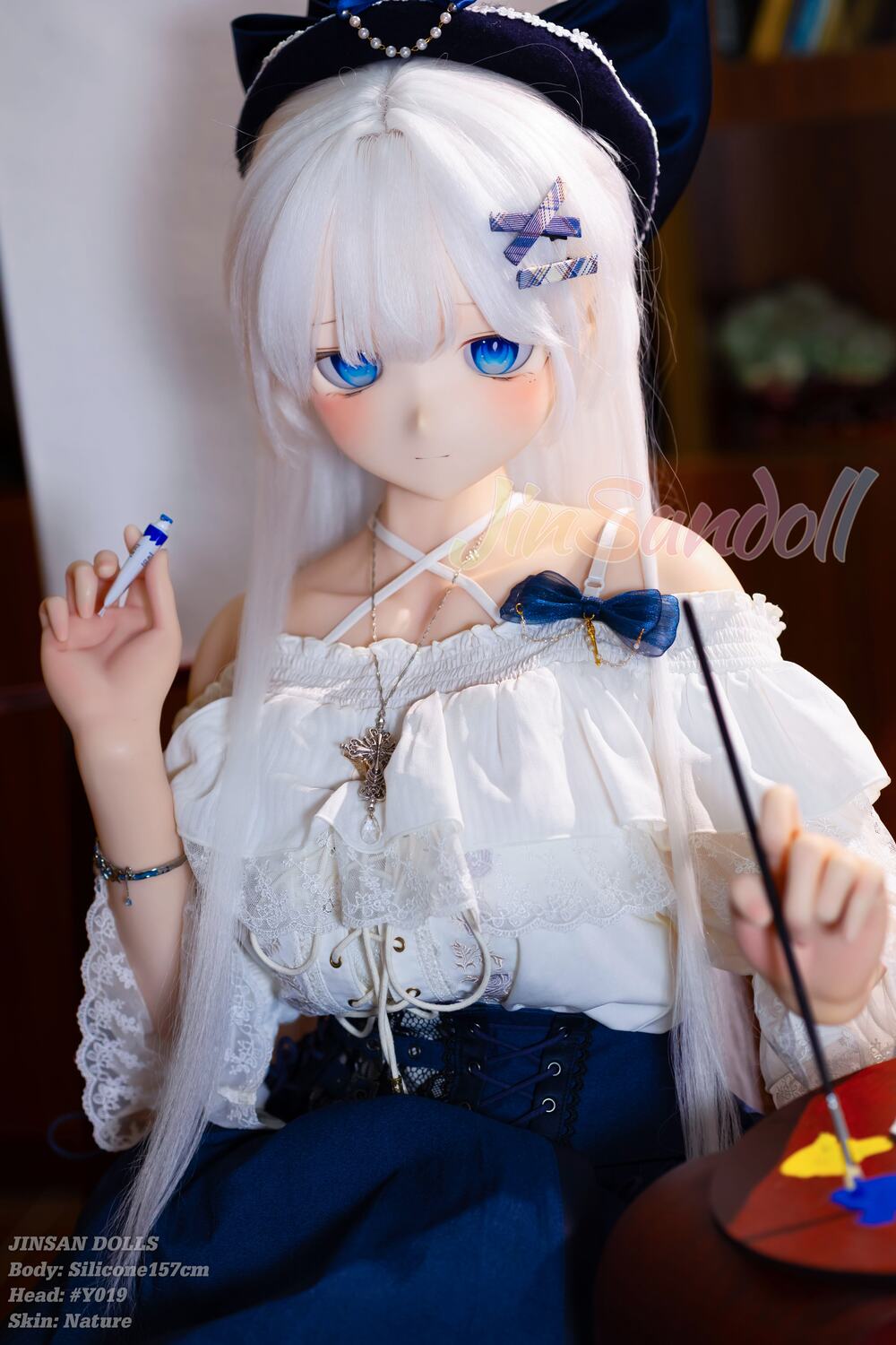 Airiya Sexpuppe mit schneeweißem Haar und blauem Kleid auf einem Stuhl sitzend