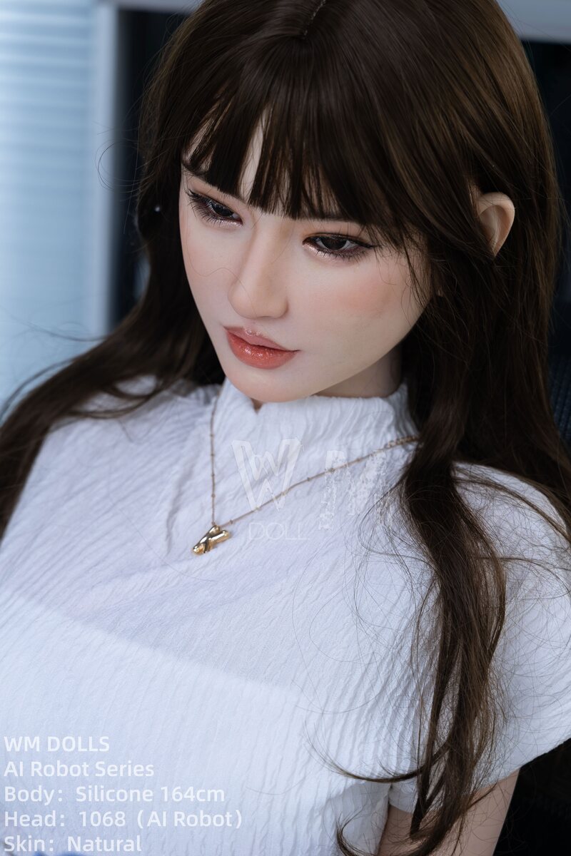 sexdoll Phebe mit langen braunen Haaren und weißer Bluse im eleganten Büro-Look