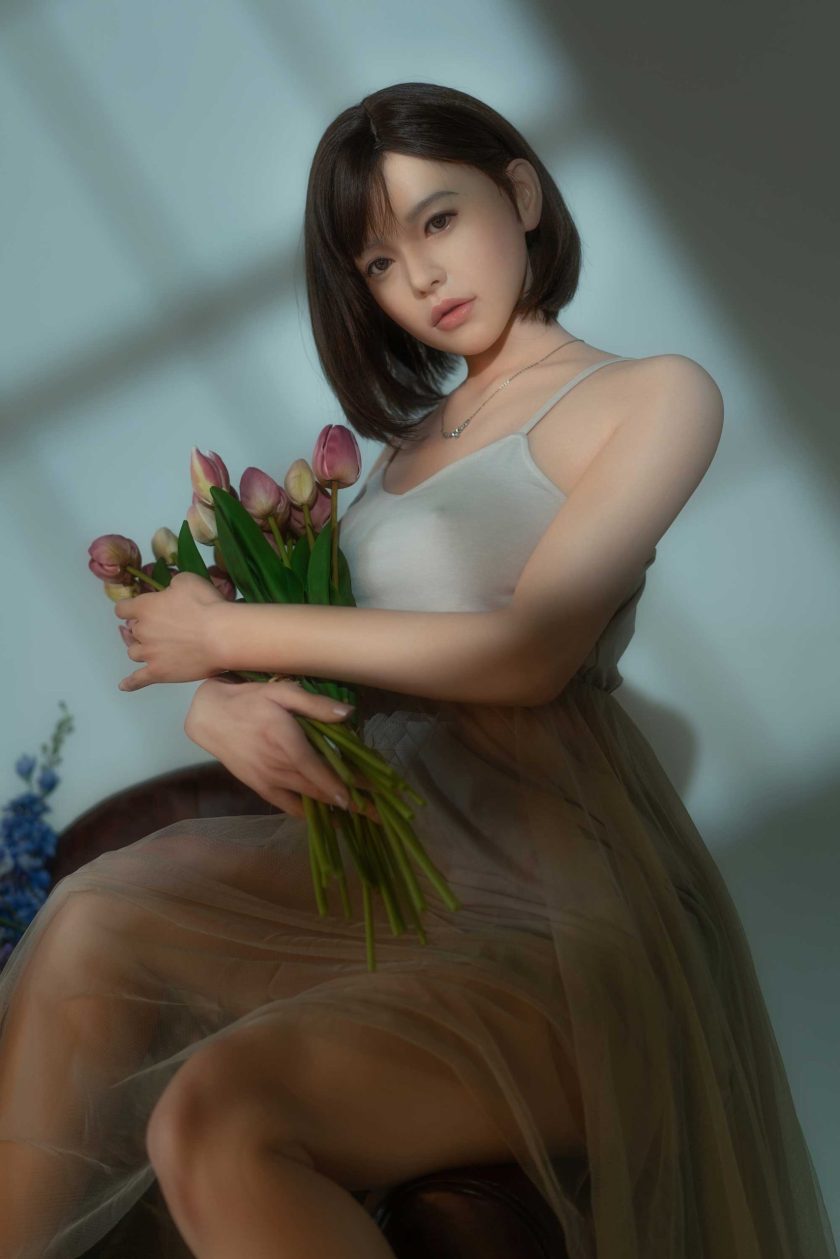 Lebensechte asiatische Sexpuppe mit kurzen Haaren und Blumen in eleganter Pose